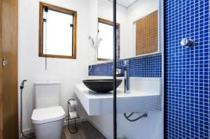 a blue tiled bathroom with a sink and a toilet at Pousada Armação de Camburi in Camburi