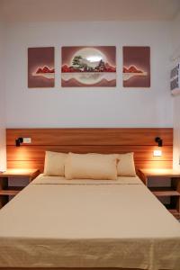 a bedroom with a bed with three paintings on the wall at Urban Chic Home Urban Chic Home with balcony in Pajo +24 photos