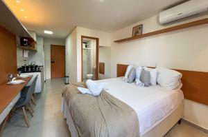a bedroom with a large bed and a kitchen at Intermares Lumiere Studio Novinho WiFi 300m Praia in Ilha da Restinga +17 photos