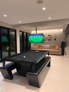a pool table in a living room with a tv at Villa Entre Verdes in Riviera de São Lourenço
