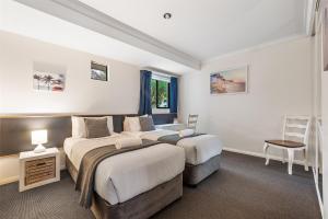 Un dormitorio con dos camas y un escritorio y una silla. en TreeTops Margaret River, en Margaret River Town