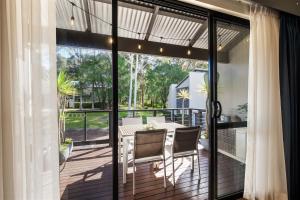 un porche cubierto con mesa y sillas en TreeTops Margaret River, en Margaret River Town