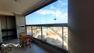 a room with a large window with a desk and a table at Apartamento Festa do Peão Barretos in Barretos