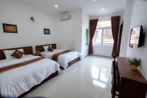a hotel room with two beds and a television at The Time Huế Homestay in Hue