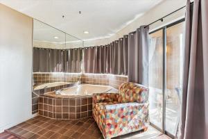 a bath room with a tub and a chair at Hibiscus F103 in Saint Augustine