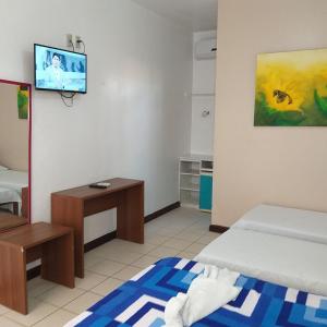 a room with two beds and a tv on the wall at Pousada Planeta Guarajuba in Guarajuba
