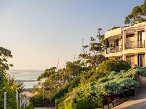 a building on a hill with the ocean in the background at Sheer Pleasure Accommodation in Smithton