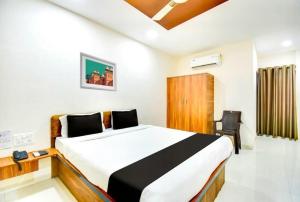 ChikalthānにあるHotel O Grand Executiveのベッドと椅子のある寝室