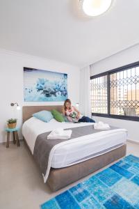 a little girl sitting on a bed in a bedroom at HaBaitBe Matityahu By Domus in Beer Sheva