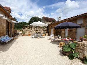 a patio with tables and chairs and umbrellas at Gîte charmant à Groléjac avec parking, WiFi et jardin clos - FR-1-616-428 in Groléjac