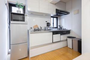 a kitchen with white cabinets and a stainless steel refrigerator at Private House NISHIOGI in Kichijōji