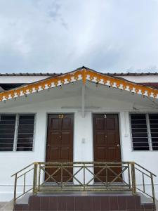 a building with two brown doors and a balcony at Villa Warisan Homestay 