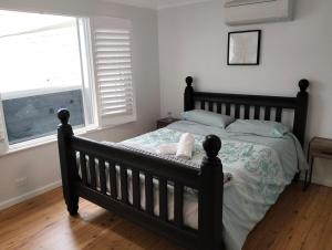 a bedroom with a black bed with a window at Family Beach House with Swim Spa in Nelson Bay +44 photos