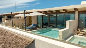 イスラ・ムヘーレスにあるBeachfront Luxe Penthouse Studio in Isla Mujeresのスイミングプールと傘付きの家