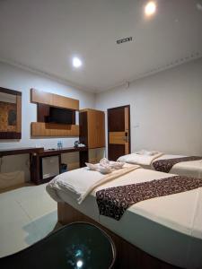a room with two beds and a desk with a computer at Hotel Diana in Lhokseumawe