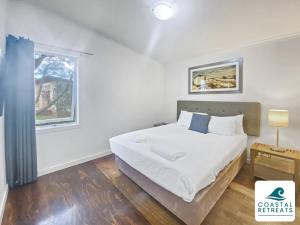 biała sypialnia z łóżkiem i oknem w obiekcie Correa Retreat - Phillip Island Resort w mieście Cowes