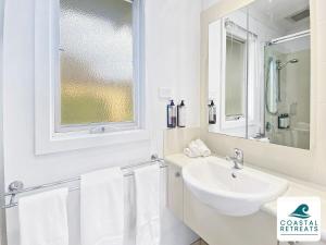 biała łazienka z umywalką i lustrem w obiekcie Correa Retreat - Phillip Island Resort w mieście Cowes +29 zdjęć