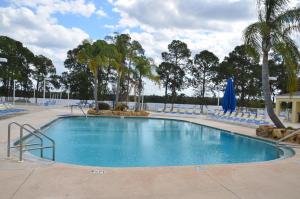 uma grande piscina com cadeiras azuis e árvores em Lake Magic Cottage 1 em Kissimmee