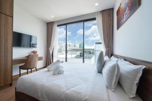 a bedroom with a large white bed with a window at BRIO Urbano Apartment in Da Nang