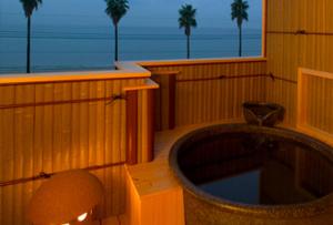 a bathroom with a tub and a window with palm trees at Mamesentaigetsu in Minamichita