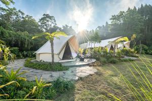 a group of tents in a field with trees at Sanctua Luxury Glamping Resort in Bedugul