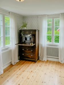 a room with a wooden dresser in a room with windows at Historic Countryside Home Near Lake In Ekeryd in Svängsta