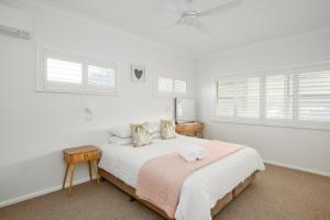 a white bedroom with a bed and two windows at Riverside Retreat in Harrington +25 photos
