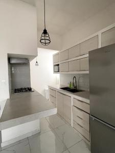 a kitchen with white cabinets and a stainless steel refrigerator at Acogedor departamento cerca de la X in Arena