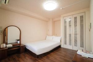 Un dormitorio con una cama blanca y un espejo. en 三ノ輪 吉原, en Tokio