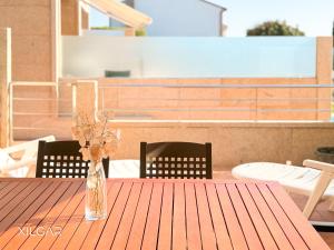 a glass vase with flowers on a wooden table at Xilgar - O Vimbieiro Chalet in Sanxenxo