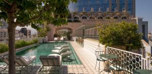 a pool on the roof of a building with tables and chairs at Albergo Hotel in Beirut