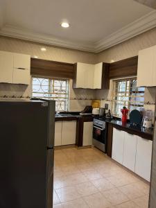 a kitchen with white cabinets and a black refrigerator at AHIL apartments in Kano