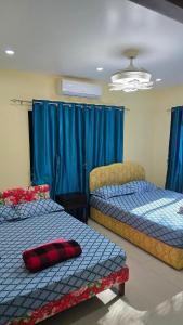 two beds in a room with blue curtains at Hasmatullah Holiday Apartments in Sigatoka