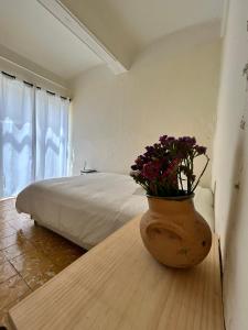 - une chambre avec un lit et un vase avec des fleurs sur une table dans l'établissement Independencia 106 - Una casa cómoda en el centro historico de Oaxaca, à Oaxaca