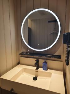 lavabo con espejo redondo encima en Hanting Hotel Beijing Fengtai Railway Station Subway Station, en Beijing