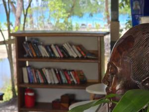 a book shelf full of books with a statue of a head at White Beach Resort Longset in Koh Rong Island