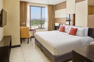 Una habitación de hotel con una cama grande y un escritorio. en Summit Hotel Tacloban, en Tacloban