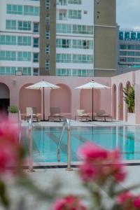 a swimming pool with chairs and umbrellas in a building at Away Bangkok Sukhumvit in Bangkok