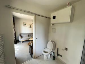 a bathroom with a toilet and a living room at appartement Mondragon in Mondragon