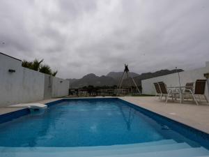 a swimming pool with chairs and a view of mountains at Al Dana, The Bay Villa in Fujairah