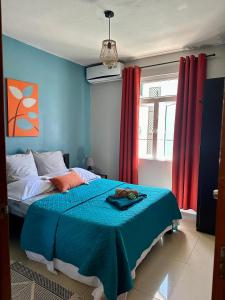 a bedroom with a bed with blue walls and red curtains at Flic en Flac Beachfront Apartment, KAZAFIBI in Flic-en-Flac