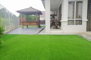 un cortile erboso con una panchina e un gazebo di Nur Banglo Homestay Port Dickson a Kampong Baharu