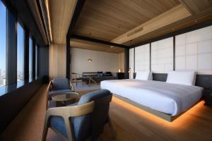 a bedroom with a bed and chairs and a desk at The Royal Park Hotel Iconic Nagoya in Nagoya