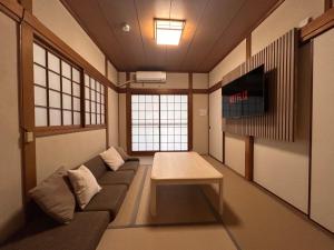 大阪市にある3LDK Entire house for rent 3 bedrooms, 2 toilets, and parking lot! Close to the station, USJ, and Expo!のソファとテーブルのあるリビングルーム