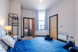 a bedroom with a blue bed and a window at Bright Flat with Wifi, Close to Beach! in Wallasey