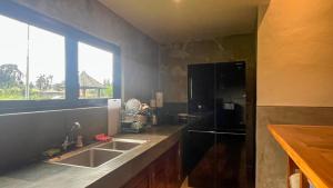 a kitchen with a sink and a black refrigerator at Villa Brahmari in Ubud
