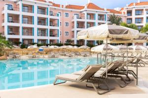 a hotel swimming pool with chairs and umbrellas at Hilton Vilamoura in Vilamoura
