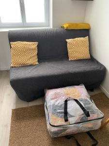 a gray couch with a bag sitting next to it at Chez Jules, appartement tout confort de 40 m2 in Denain