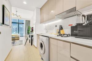 eine weiße Küche mit Waschmaschine und Trockner. in der Unterkunft Elegant Studio with Pool Access & Private Terrace in Dubai