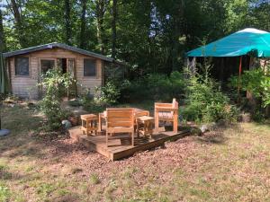 a wooden deck with chairs and a table in a yard at Yourte Les Hulottes en Comminges in Juzet-dʼIzaut